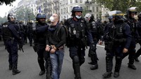Polisi mengamankan seorang demonstran yang ikut serta dalam aksi unjuk rasa memprotes kebijakan wajib memiliki paspor COVID-19 yang berujung ricuh di kawasan Paris, Prancis. AP Photo/Adrienne Surprenant.