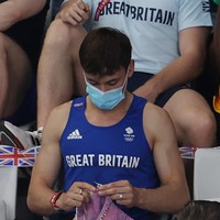 Sebuah pemandangan unik terlihat dalam pertandingan loncat indah wanita di Olimpiade Tokyo 2020. Atlet kenamaan Tom Daley kedapatan menonton laga tersebut selagi tangannya sibuk merajut benang. Foto: Getty Images/Clive Rose