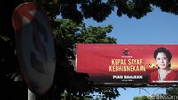 Baliho Puan Maharani memiliki latar pemandangan pantai dan matahari terbenam yang dilintasi sekawanan burung.