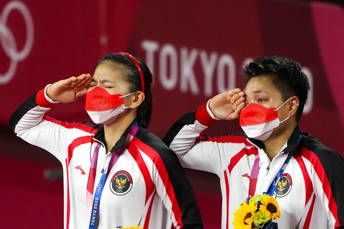 Gold medalists Greysia Polii, left, and Apriyani Rahayu from Indonesia listen to the national anthem during the medals ceremony of the womens doubles gold medal match at the 2020 Summer Olympics, Monday, Aug. 2, 2021, in Tokyo, Japan. (AP Photo/Markus Schreiber)