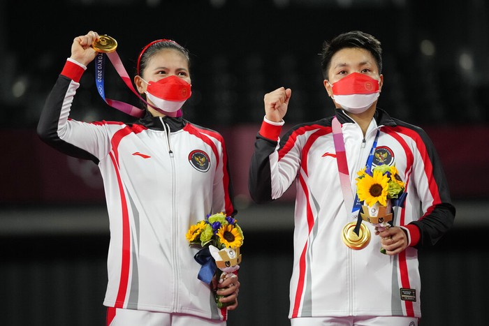 Gold medalists Greysia Polii, left, and Apriyani Rahayu from Indonesia listen to the national anthem during the medals ceremony of the womens doubles gold medal match at the 2020 Summer Olympics, Monday, Aug. 2, 2021, in Tokyo, Japan. (AP Photo/Markus Schreiber)