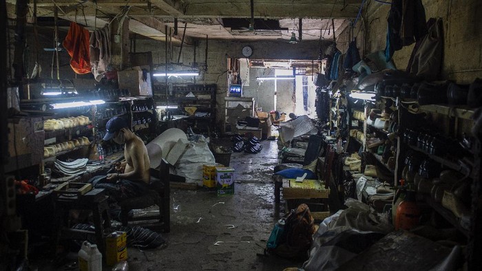 Pekerja menyelesaikan pesanan sepatu di bengkel kerja pembuatan sepatu milik Ardian di Perkampungan Industri Kecil (PIK) Penggilingan, Cakung, Jakarta Timur, Senin (2/8/2021). Adanya Pemberlakuan Pembatasan Kegiatan Masyarakat (PPKM) menyebabkan usahanya menurun hingga 70 persen dikarenakan toko-toko dan pusat perbelanjaan yang mengambil sepatu darinya tidak boleh berjualan. ANTARA FOTO/M Risyal Hidayat/foc.