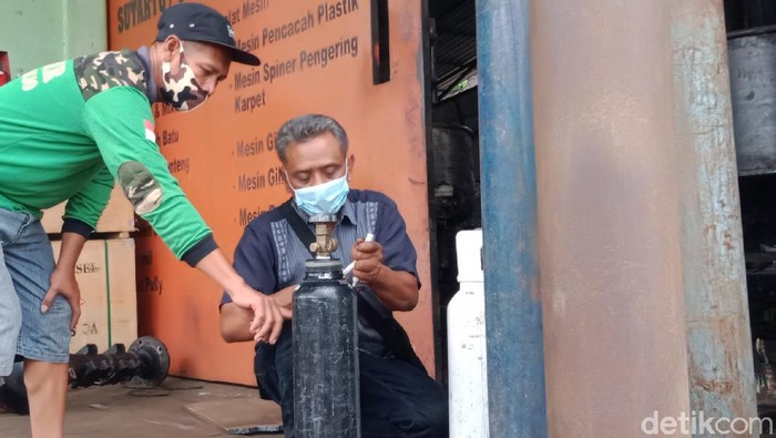 Sutarto saat mengisi tabung oksigen salah seorang warga yang datang ke bengkelnya di Klaten, Senin (2/8/2021)