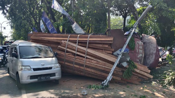 Truk bermuatan kayu terguling di Gresik diduga karena rem blong. Akibatnya, muatan tersebut menimpa sebuah mobil dan dua pengendara motor.