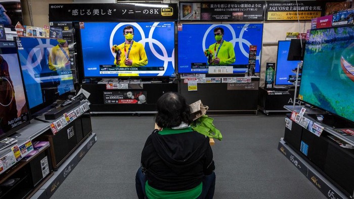 TOKYO, JAPAN - JULY 29: A woman watches Olympics games on televisions at an electronics retail store on July 29, 2021 in Tokyo, Japan. Fans have been barred from most Olympic events due to the Covid-19 pandemic, which also caused the Games yearlong postponement. (Photo by Yuichi Yamazaki/Getty Images)