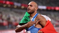 Sambil memegang bendera Italia, begini ekspresi Jacobs setelah menang. Patrick Smith/Getty Images.