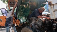 Sopir tengah memperbaiki mesin truk.