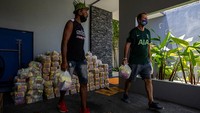 Relawan memuat berbagai macam bahan makanan dan perlengkapan kebersihan ke dalam kantung Life Bags”  di Phuket, Thailand.