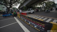 Sejumlah pengendara kendaraan bermotor melewati celah penyekatan Jalan Jatibaru Raya saat masa Pemberlakuan Pembatasan Kegiatan Masyarakat (PPKM) Level 4 di Tanah Abang, Jakarta, Selasa (3/8/2021).