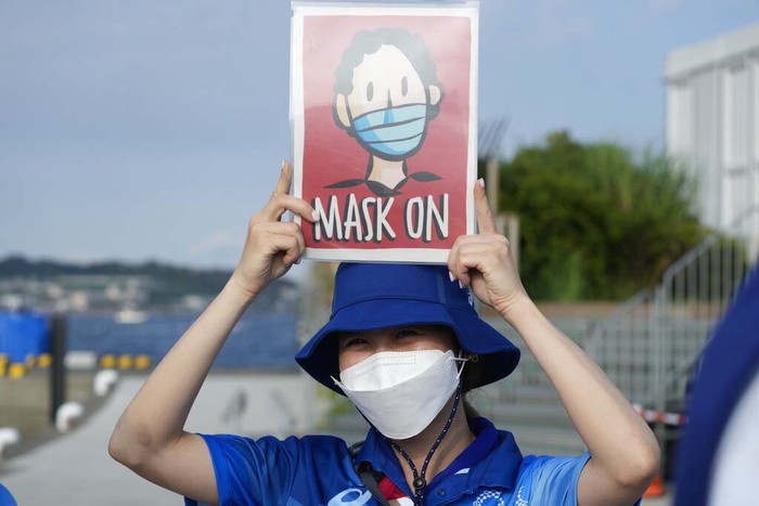 A volunteer cleans seats meant for spectators at the Ariake Tennis Center ahead of the 2020 Summer Olympics, Friday, July 23, 2021, in Tokyo, Japan. (AP Photo/Seth Wenig)