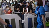 eorang relawan menyemprotkan disinfektan kepada penonton yang akan masuk. AP Photo/Christophe Ena.