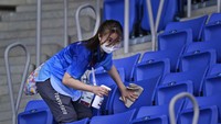 Seorang relawan menyemprotan cairan disinfektan ke kursi penonton di stadion tenis. AP Photo/Seth Wenig