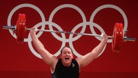 Laurel Hubbard saat beraksi di cabang angkat besi Olimpiade Tokyo. Komite Olimpiade Internasional (IOC) membolehkan atlet transgender berlaga sejak 2004. Pada 2015, peraturan tersebut dipertegas lagi bahwa atlet yang bertransisi dari laki-laki menjadi perempuan dapat bertanding di nomor putri tanpa harus menjalani operasi kelamin. Chris Graythen/Getty Images