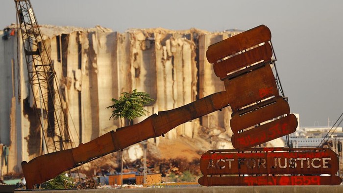 Monumen Puing-puing Ledakan Lebanon, Simbol Duka Beirut A justice symbol monument is seen in front of towering grain silos that were gutted in the massive August 2020 explosion at the port that claimed the lives of more than 200 people, in Beirut, Lebanon, Wednesday, Aug. 4, 2021. A year after the deadly blast, families of the victims are consumed with winning justice for their loved ones and punishing Lebanon's political elite, blamed for causing the disaster through their corruption and neglect. (AP Photo/Hussein Malla)
