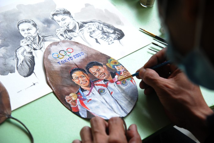 Pelukis Teddy Arte menunjukkan lukisan daun kering ganda putri Indonesia peraih medali emas Olimpiade Tokyo 2020, Greysia Polii dan Apriyani Rahayu di Desa Cilebut Timur, Sukaraja, Kabupaten Bogor, Jawa Barat, Kamis (5/8/2021). Lukisan daun kering yang diselesaikan dalam waktu dua hari tersebut sebagai bentuk penghargaan seniman atas prestasi ganda putri Indonesia yang berhasil meraih medali emas pada cabang olahraga bulutangkis Olimpiade Tokyo 2020. ANTARA FOTO/Arif Firmansyah/aww.