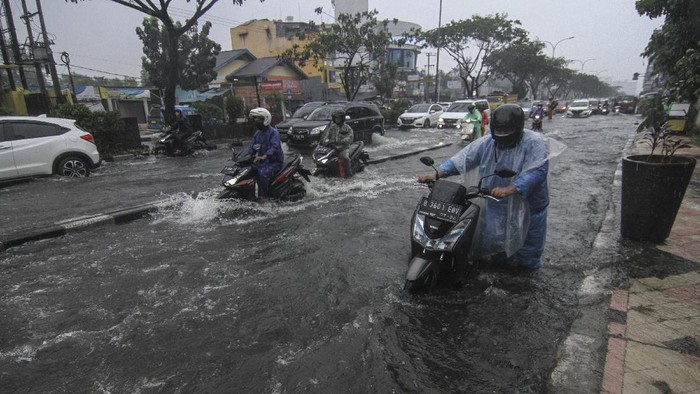 Pengendara mendorong sepeda motor yang mogok saat melintasi genangan air di Jalan Margonda Raya, Depok, Jawa Barat, Kamis (5/8/2021). Genangan setinggi 30 cm hingga 60 cm merendam kawasan tersebut akibat tingginya curah hujan serta drainase yang buruk. ANTARA FOTO/Asprilla Dwi Adha/aww.