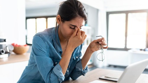 Shot of stressed business woman working from home on laptop looking worried, tired and overwhelmed.