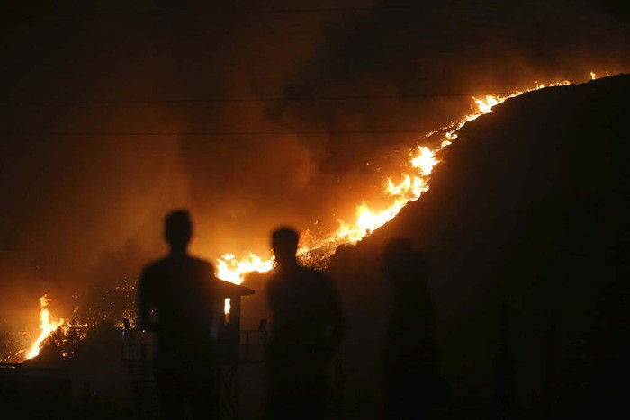 Turkey Wildfire People stand in front of Kemerkoy Thermal Power Plant with the blaze approaching in the background, in Milas, Mugla, Turkey, Tuesday, Aug. 3, 2021. Turkish President Recep Tayyip Erdoganβs government is facing increased criticism over its apparent poor response and inadequate preparedness for large-scale wildfires that have left eight people dead and forced thousands to flee their homes. (AP Photo/Emre Tazegul)