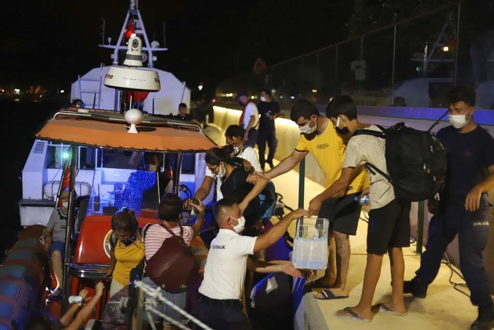 People wait to be evacuated by boats after wildfires reached the Kemerkoy Power Plant, a coal-fueled power plant, in Milas in southwest Turkey, late Wednesday, Aug. 4, 2021. (AP Photo/Cem Tekkesoglu)