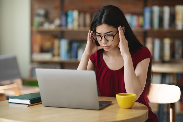 Asian Nerd Student Girl Studying Online With Laptop In Cafe, Touching Temples, Trying To Concentrate, Preparing For Difficult Exam