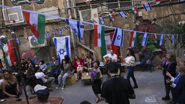 Israelis celebrating the Persian New Year, known as Nowruz, at a restaurant's backyard decorated with Israeli and Iranian flags, in Tel Aviv, Friday, March 19, 2021. The party was broadcast live from Tel Aviv to Iran on the Iran International TV channel. Shai Filer, the organizer, said the party was to 