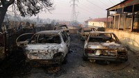 Mobil yang terbakar setelah kebakaran hutan di daerah Varibobi, Athena utara, Yunani. AP Photo/Thanassis Stavrakis.