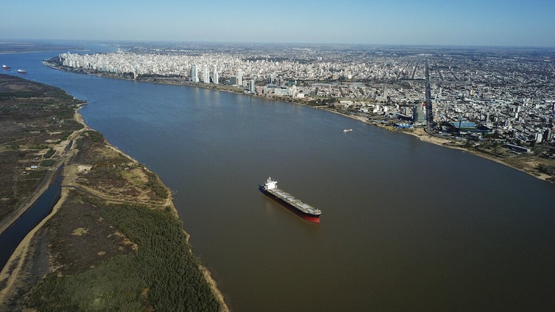 Birds fly over a man taking photos of the exposed riverbed of the Old Parana River, a tributary of the Parana River during a drought in Rosario, Argentina, Thursday, July 29, 2021. (AP Photo/Victor Caivano)