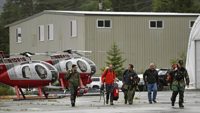Ketchikan Volunteer Rescue Squad personnel land and disembark from a Hughes 369D helicopter on Thursday, Aug. 5, 2021, at Temsco Helicopters Inc in Ketchikan, Alaska. The KVRS, U.S. Coast Guard, Alaska State Troopers and U.S. Forest Service responded to a radio beacon alert from a downed Southeast Aviation de Havilland Beaver float plane that was carrying five passengers from the Holland America Line cruise ship Nieuw Amsterdam, according to Coast Guard, Holland America and KVRS information. The sightseeing plane crashed Thursday in southeast Alaska, killing all six people on board, the U.S. Coast Guard said. (Dustin Safranek/Ketchikan Daily News via AP)