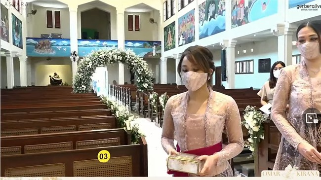 Selama prosesi pemberkatan kakaknya, Dita Karang memakai atasan bernuansa lilac yang dipadukan dengan kain bernuansa coklat. Sedangkan untuk selendang yang membalut pinggangnya dipilih warna marun. Foto: YouTube Kirana Karang