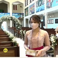 Selama prosesi pemberkatan kakaknya, Dita Karang memakai atasan bernuansa lilac yang dipadukan dengan kain bernuansa coklat. Sedangkan untuk selendang yang membalut pinggangnya dipilih warna marun. Foto: YouTube Kirana Karang