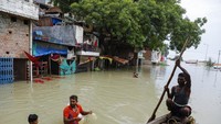 Warga desa mendayung perahu di jalanan dekat aliran Sungai Gangga di Prayagraj, India. Sungai itu meluap akibat hujan deras.