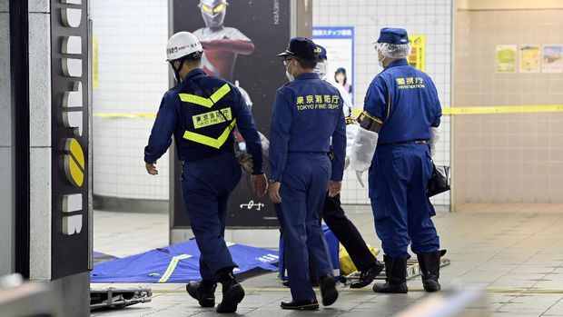 Tokyo Fire Department personnel and a police investigator, right, move toward a platform at Soshigaya Okura Station after stabbing on a commuter train, in Tokyo Friday, Aug. 6, 2021. A man with a knife stabbed passengers on a commuter train Friday and was arrested by police after fleeing, fire department officials and news reports said. (Kyodo News via AP)