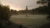 Tampak pesawat mengambil air dari danau untuk proses pemadaman kebakaran.