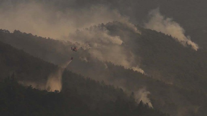 A firefighting helicopter pours water onto a wildfire in northern Athens, Saturday, Aug. 7, 2021.  Wildfires rampaged through Greek forests for yet another day Saturday, threatening homes and triggering more evacuations a day after hundreds of people were plucked off beaches by ferries in a dramatic overnight rescue. (AP Photo/Lefteris Pitarakis)