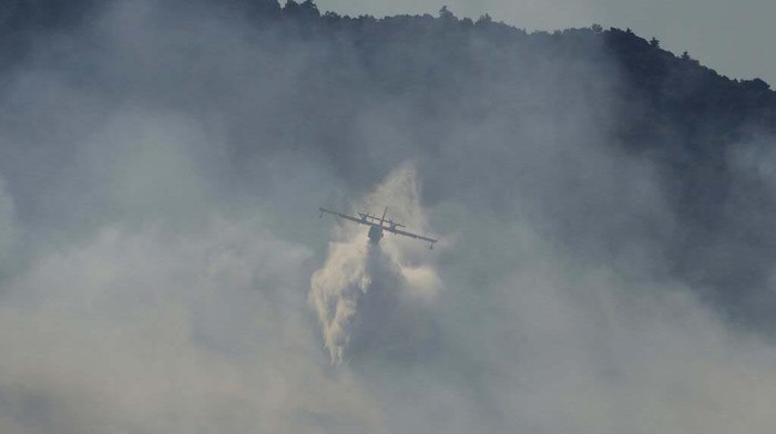 A firefighting helicopter pours water onto a wildfire in northern Athens, Saturday, Aug. 7, 2021.  Wildfires rampaged through Greek forests for yet another day Saturday, threatening homes and triggering more evacuations a day after hundreds of people were plucked off beaches by ferries in a dramatic overnight rescue. (AP Photo/Lefteris Pitarakis)