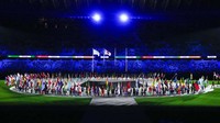 Tak seperti di upacara pembukaan ketika setiap negara dipanggil satu per satu, parade bendera kali ini langsung masuk ke tengah lapangan. Setiap negara diwakilkan satu pembawa bendera. AP/Charlie Riedel 