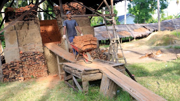 Pekerja membongkar muat batu bata usai proses pembakaran di salah satu tempat produksi di Desa Lambada Peukan, Darussalam, Aceh Besar, Aceh, Minggu (8/8/2021). Produksi batu bata sejak beberapa bulan terakhir mengalami peningkatan hingga 80 persen dari biasanya seiring meningkatnya permintaan untuk pembangunan perumahan bersubsidi di kawasan itu. ANTARA FOTO/Syifa Yulinnas/wsj.
