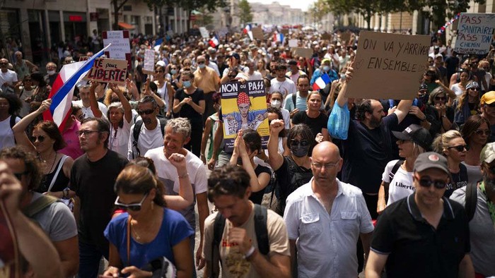 Tourists watch a protest from a sightseeing bus in Marseille, southern France, Saturday, Aug. 7, 2021. Thousands of people are marching in Paris and other French cities during a fourth consecutive week of protests against COVID-19 entrance requirements. The demonstrations on Saturday come days after France's Constitutional Council upheld most provisions of a new law that expands the locations where health passes are needed. (AP Photo/Daniel Cole)