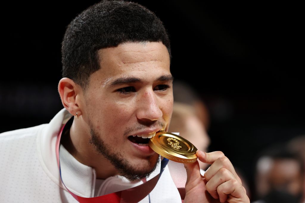 SAITAMA, JAPAN - AUGUST 07: Devin Booker of Team United States bites his gold medal during the Men's Basketball medal ceremony on day fifteen of the Tokyo 2020 Olympic Games at Saitama Super Arena on August 07, 2021 in Saitama, Japan. (Photo by Kevin C. Cox/Getty Images)