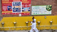 Sepasang kekasih berjalan melewati wastafel yang terpasang di tengah pandemi virus corona di Corabastos, Bogota, Kolombia.