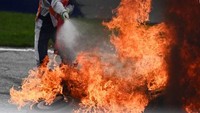 Track marshal memadamkan api yang melalap motor Savadori dan Pedrosa.  (Foto: AFP/ERWIN SCHERIAU)