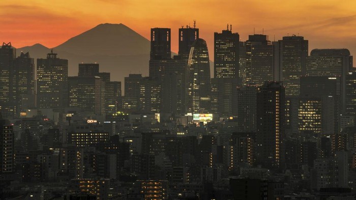 TOKYO, JAPAN - DECEMBER 23: Mount Fuji is seen behind the city skyline at dusk on December 23, 2020 in Tokyo, Japan. The Tokyo Metropolitan Government announced 748 new cases of Covid-19 coronavirus today as infections continue to fluctuate nationwide. To date, Japan has recorded 203,732 infections, 2,877 and 169,186 recoveries from the virus. (Photo by Carl Court/Getty Images)