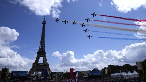 The French Aerial Patrol fly by the Eiffel Tower and over the Olympics fan zone in Paris, Sunday, Aug. 8, 2021. Celebrations were held in Paris Sunday as part of the handover ceremony of Tokyo 2020 to Paris 2024, as Paris will be the next Summer Games host in 2024. The passing of the hosting baton will be split between the Olympic Stadium in Tokyo and a public party and concert in Paris. (AP Photo/Francois Mori)