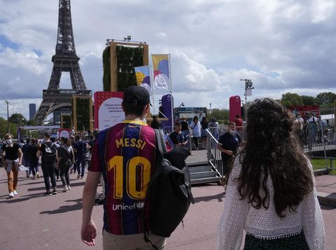 A spectator wears a Lionel Messi soccer jersey as he walks in the Olympics fan zone in the Trocadero Gardens in front of the Eiffel Tower in Paris, Sunday, Aug. 8, 2021. Celebrations were held in Paris Sunday as part of the handover ceremony of Tokyo 2020 to Paris 2024, as Paris will be the next Summer Games host in 2024. The passing of the hosting baton will be split between the Olympic Stadium in Tokyo and a public party and concert in Paris. (AP Photo/Francois Mori)