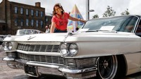 Tampak seorang wanita berpose di mobil Cadilac Coupe de Ville lansiran 1967.  