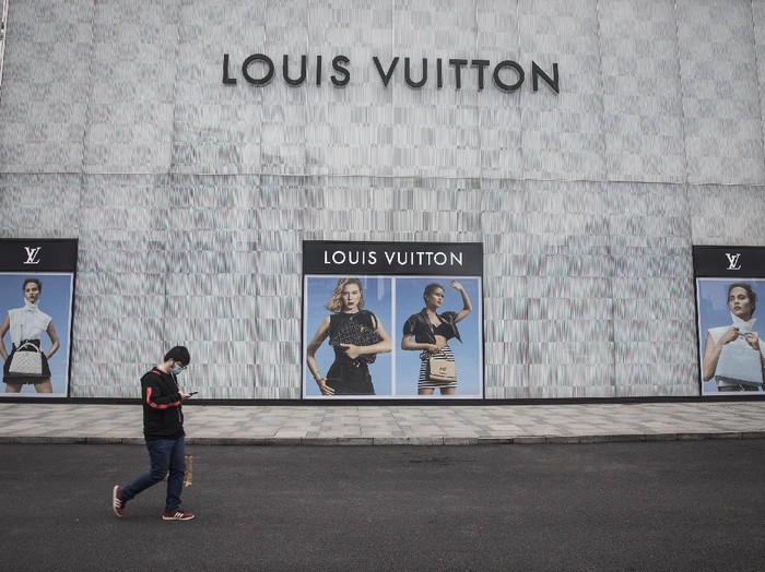 WUHAN, CHINA - MARCH 30: (CHINA OUT) A man wearing a face mask passes a Louis Vuitton store outside Wuhan international plaza on March 30, 2020 in Hubei Province, China. Wuhan, the central Chinese city where the coronavirus (COVID-19) first emerged last year, will lift the lockdown on April 8, local media reported. (Photo by Getty Images)