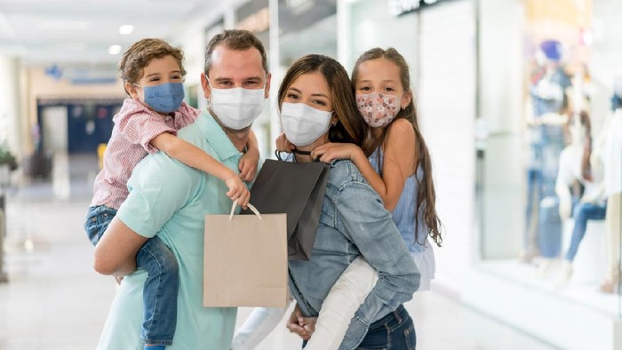 Portrait of a happy Latin American family shopping at the mall wearing facemasks during the COVID-19 pandemic â reopening of businesses concepts
