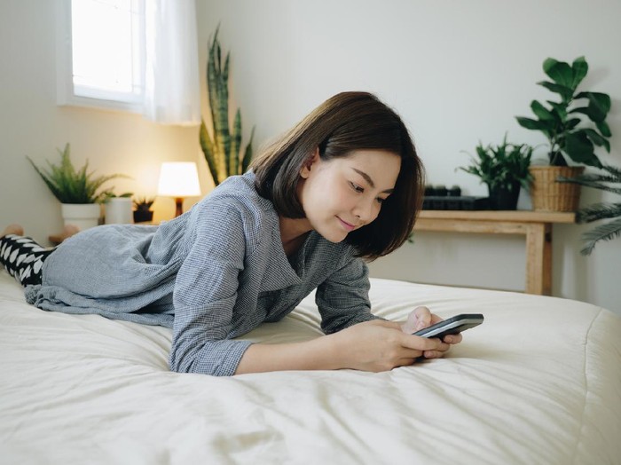 1295105194 Close up of a depressed Caucasian young woman sitting at home, reading some bad news on her smart phone, feeling sad and worried