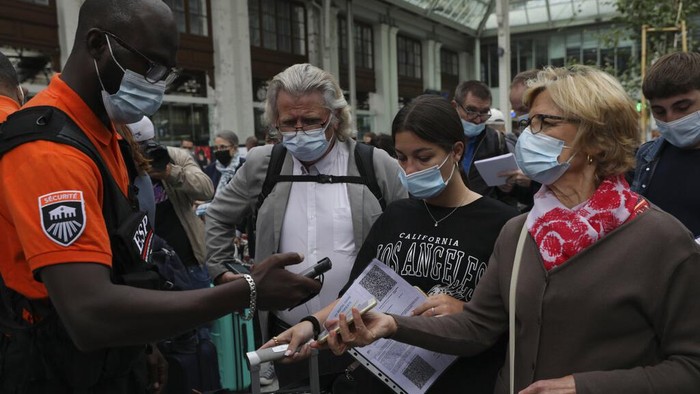 A waiter checks clients' health passes at a restaurant in Paris, Monday Aug.9, 2021. People in France are now required to show a QR code proving they have a special virus pass to enjoy restaurants and cafes or travel across the country. The measure is part of a government plan to encourage more people to get the vaccine and to slow down a surge in infections, as the highly contagious delta variant now accounts for most cases in France.(AP Photo/Adrienne Surprenant)