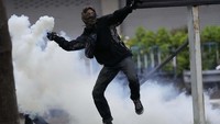 Massa melemparkan kembali gas air mata yang ditembakan polisi. AP Photo/Sakchai Lalit.